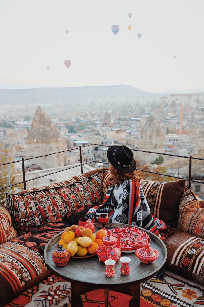 Service 2 Woman enjoys Cappadocia's landscape from a vibrant terrace overlooking hot air balloons and unique formations.