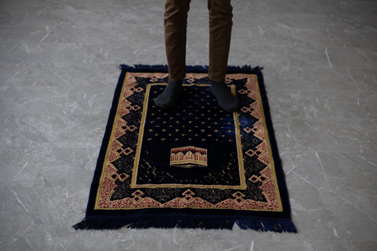 Accueil 1 From above of crop anonymous male standing on prayer mat on floor at home before praying